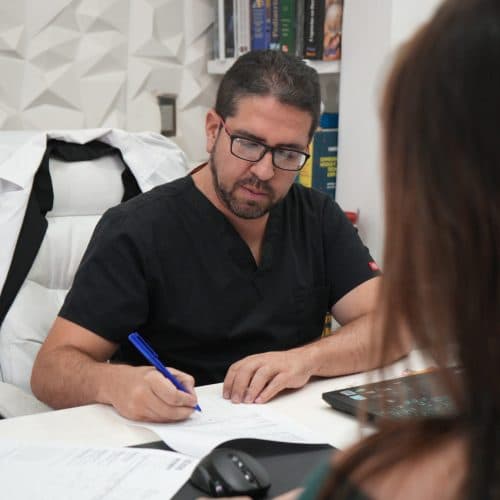 Dr. Santiago López Vega tomando notas durante la valoración médica.